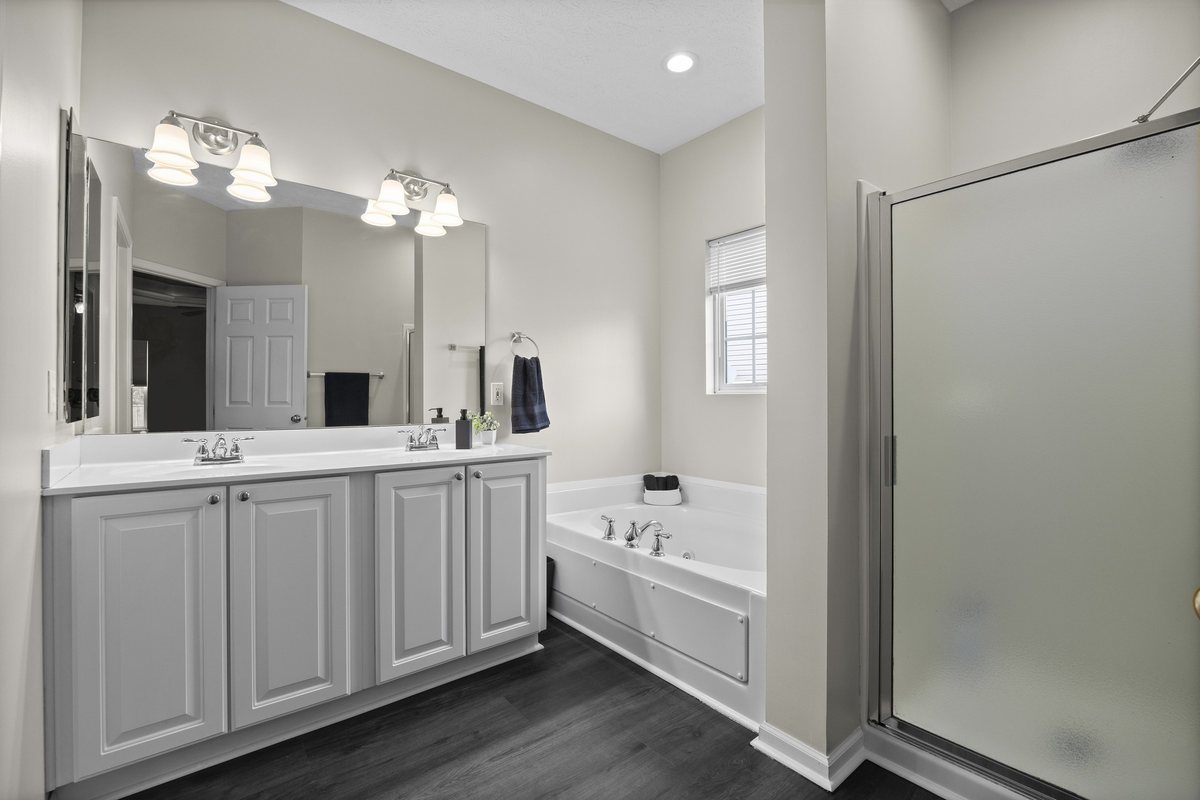 Primary bathroom with double vanity, soaking tub, and separate shower