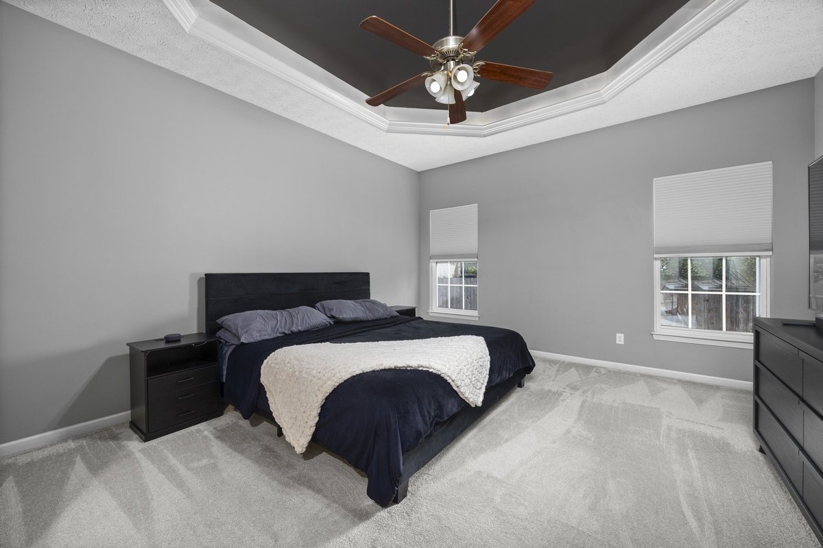 Primary bedroom with tray ceiling and ceiling fan